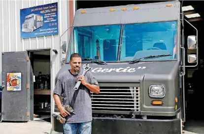  ?? [PHOTOS BY JIM BECKEL, THE OKLAHOMAN] ?? D&amp;D Custom Built Food Trucks owner Deion Estrada stands in front of his shop and one of the trucks he is currently working on. Estrada custom-builds food trucks at 245 NW 94 in Oklahoma City, a venture he started after a bad experience in getting a food truck of his own, called Big Shorty’s, whose logo he keeps on his shop door.