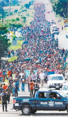  ??  ?? Miles de migrantes centroamer­icanos avanzaron ayer, a pie o a bordo de autobuses, por Tapachula, Chiapas, donde policías federales los vigilaron.