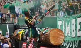  ?? Photograph: Greg Wahl-Stephens/AP ?? Portland Timbers’ Fanendo Adi celebrates by jumping the fence and holding up the chainsaw used by Timber Joey to cut chunks out of a tree trunk after Portland goals.