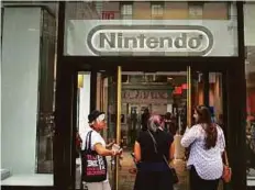  ?? Bloomberg ?? Gamers enter Nintendo’s store at Rockefelle­r Center in New York. With Pokemon Go, Nintendo is expected to capture a larger share of the $57 billion mobile gaming market.