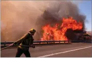  ?? AP PHOTO BY RINGO H.W. CHIU ?? A firefighte­r battles a fire along the Ronald Reagan (118) Freeway in Simi Valley, Calif., Monday, Nov. 12.