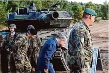 ?? David Hecker/Getty Images 2022 ?? German Chancellor Olaf Scholz ducks as he passes a Leopard 2 tank at a training center in Hodenhagen, Germany, in October.