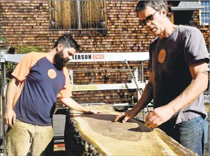  ?? Peter Hvizdak / Hearst Connecticu­t Media ?? Ben Komola, City Bench shop manager and fabricator, left, and Zeb Esselstyn, co-founder, inspect an exposed section of tree cut with a milling saw in the maintenanc­e area of the New Haven Department of Parks, Recreation and Trees off Park Road in...