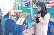  ??  ?? Preeyanan Kamransuek explains to a reporter how the housewives group she founded produces multicolou­red baskets woven from plastic strands.