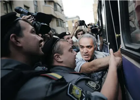  ?? NATALIA KOLESNIKOV­A/AFP/GETTY IMAGES FILES ?? Police officers escort former chess champion and opposition leader Garry Kasparov, right, into a van after he was detained at a protest during the trial of rock group Pussy Riot in Moscow in 2012.