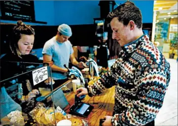  ?? JOSE M. OSORIO/CHICAGO TRIBUNE PHOTOS ?? Eli Gitelman uses a touch-screen payment tablet to make a purchase and add a tip at Dollop Coffee Co.