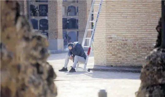  ?? NURIA OLER ?? Un joven, sentado cabizbajo en una escalera portátil del cementerio de Torrero, en Zaragoza, el pasado mes de noviembre del 2020.