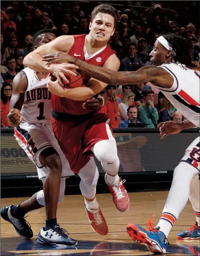  ?? AP/TODD J. VAN EMST ?? Arkansas Razorbacks guard Dusty Hannahs tries to drive the lane while defended by Auburn’s Jared Harper (left) and T.J. Dunans on Saturday night in Auburn, Ala. Hannahs scored 18 points in the Razorbacks’ 79-68 victory over the Tigers.