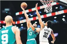  ?? — AFP photo ?? Tatum (centre) goes to the basket as Nic Claxton of the Brooklyn Nets defends during the second half at Barclays Centre in the Brooklyn borough of New York City.