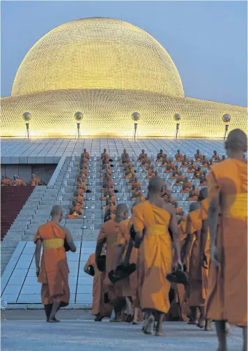  ??  ?? SEEING THE LIGHT: Buddhist monks find a place to sit before morning prayers to mark Makha Bucha Day at Wat Phra Dhammakaya.