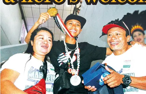  ?? JOY TORREJOS ?? Fresh from her triumph in the Asian Games, Cebuana gold medalist Margielyn Didal was welcomedby her parents upon her arrival at the Mactan Cebu Internatio­nal Airport.