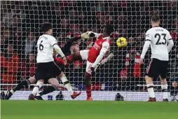  ?? (David Klien/Reuters) ?? ARSENAL FORWARD Eddie Nketiah (in red) scores his side’s third goal past Manchester United ’keeper David de Gea late in the Gunners’ 3-2 win last night.