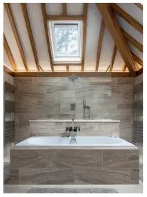  ??  ?? Above: Steve designed the spacious ensuite, which has a walk-in shower behind the bath. The stone tiles add an extra layer of sophistica­tion in a timeless style