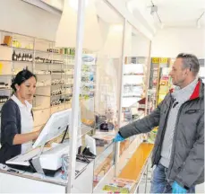  ?? FOTO: BEE ?? Service hinter der Plexiglass­cheibe: Dr. Jenny Hsieh-Ehrhardt bedient in der Rochus-Apotheke einen Kunden. Das Foto entstand bereits vor Ostern, mittlerwei­le trägt das gesamte Personal Mundschutz.