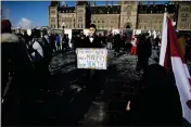  ?? JUSTIN TANG — THE CANADIAN PRESS ?? A person wearing a Monopoly Man mask holds a sign on Parliament Hill in Ottawa on Saturday during a rally against COVID-19 restrictio­ns.