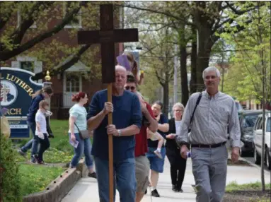  ?? MARIAN DENNIS — MEDIANEWS GROUP ?? Parishione­rs from various churches follow behind a large wooden cross as they walk around downtown Pottstown, praying for various causes during the annual Good Friday Procession­al.