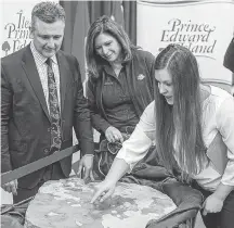  ?? SUBMITTED ?? Science educator Laura MacNeil points out the dimetrodon fossil’s patterns to Finance Minister Heath MacDonald and Parks Canada superinten­dent Karen Jans.