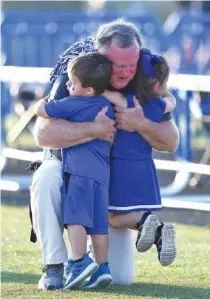  ?? STAFF PHOTO BY ROBIN RUDD ?? Ringgold football coach Robert Akins gets a hug from his grandkids Bradley and Gracie Longmire before a home game this past Sept. 20 against Lakeview-Fort Oglethorpe.