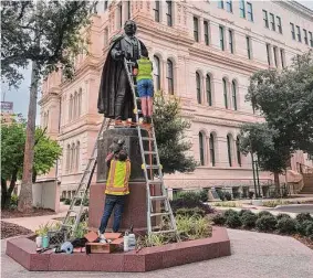  ?? City of San Antonio/Department of Arts and Culture ?? Autumn Seleh, on ladder, and her husband, Simon, work on cleaning the Moses Austin statue behind City Hall.