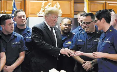  ?? Susan Walsh ?? The Associated Press President Donald Trump is presented with a challenge coin Thursday as he meets on Thanksgivi­ng Day with members of the U.S. Coast Guard stationed at the Lake Worth inlet in Riviera Beach, Fla.