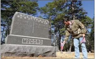  ?? (Arkansas Democrat-Gazette/Bill Bowden) ?? Koltin Massie, commander of the Sons of Confederat­e Veterans’ Seaborn Jones Cotten Camp 2303, puts Confederat­e flags on the graves of Confederat­e veterans Friday in Eureka Springs Cemetery. Seaborn Jones Cotten, who fought for the Confederac­y, was Massie’s fourth great-grandfathe­r. He is buried in Louisiana.