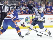  ?? AP ?? The Blues' Vladimir Tarasenko, right, takes a shot past the Islanders' Scott Mayfield on Monday.