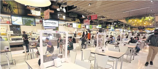 ?? VARUTH HIRUNYATHE­B ?? Vendors at the food court in The Mall Bang Kapi department store in Bangkok ramp up Covid-19 preventive measures at dining tables after City Hall threatened to close eateries for 14 days for letting their guard down.