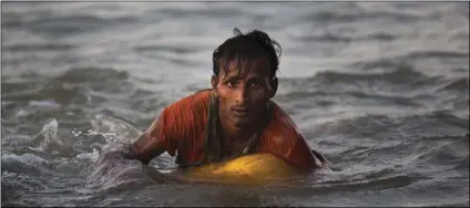  ??  ?? In this Nov. 4, photo, Rohingya Muslim Abdul Karim, 19, uses a yellow plastic oil container as a flotation device as he swims the Naf river while crossing the Myanmar-Bangladesh border in Shah Porir Dwip, Bangladesh. Rohingya Muslims escaping the...