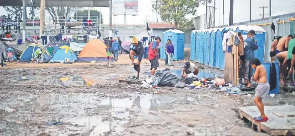  ??  ?? Miembros de la caravana migrante se bañan al aire libre en el campamento instalado en la Unidad Deportiva Benito Juárez, donde ya se encuentran más de 6 mil personas.