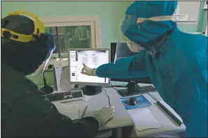  ??  ?? Medical workers look at an X-ray of lungs. (AP/Evgeniy Maloletka)