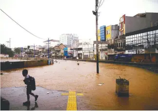  ?? REUTERSPIX ?? A student on his way to school walks near an inundated street in Jakarta yesterday.