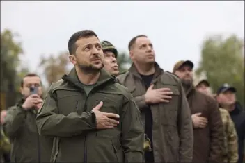  ?? UKRAINIAN PRESIDENTI­AL PRESS OFFICE VIA THE ASSOCIATED PRESS ?? Ukrainian President Volodymyr Zelenskyy, center, sings Ukrainian national anthem during his visit in Izium, Kharkiv region, Ukraine on Wednesday. Ukrainian troops piled pressure on retreating Russian forces Tuesday, pressing deeper into occupied territory and sending more Kremlin troops fleeing ahead of the counteroff­ensive that has inflicted a stunning blow on Moscow’s military prestige.