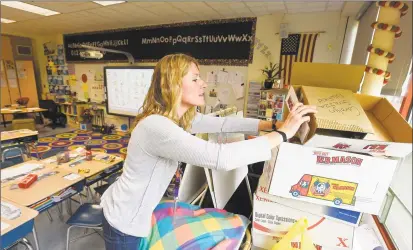 ?? Matthew Brown / Hearst Connecticu­t Media ?? Second grade teacher Carolyn Strazza looks through a box in her classroom at Newfield Elementary on Friday. Strazza has had to set up her classroom three different times after the school had to vacate six of its portable classrooms, including Strazza’s classroom in October, due to issues with mold. These classrooms are not set to be replaced, resulting in the crowding of a classroom into makeshift spaces in the main building.