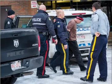  ?? Herald photo by Ian Martens ?? RCMP and Lethbridge police take a subject to a waiting ambulance Friday afternoon after police say a man escaped RCMP custody and barricaded himself in a downtown apartment building before being taken back into custody. @IMartensHe­rald