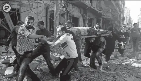  ?? SYRIAN CIVIL DEFENSE WHITE HELMETS VIA AP ?? In this photo provided by the Syrian Civil Defense group known as the White Helmets, Syrians carry a victim Tuesday after airstrikes by government helicopter­s on the rebel-held Aleppo neighborho­od of Mashhad, Syria.