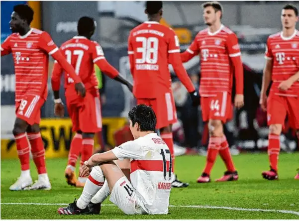  ?? Foto: Marijan Murat/dpa ?? Genki Haraguchi sitzt auf dem Rasen des Stuttgarte­r Stadions und versteht die Welt nicht mehr, während sich die Bayern-riege nach dem Sieg und einer gelungenen Generalpro­be für das Champions-league-duell gegen Paris freut.