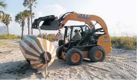  ?? DR. VON D. MIZELL-EULA JOHNSON STATE PARK/COURTESY ?? State park workers remove a buoy that washed ashore in Dania Beach days after Hurricane Irma passed through. The writing on it indicates it may be Russian.