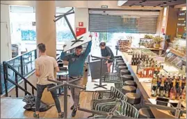  ?? SAMUEL ARANDA/THE NEW YORK TIMES ?? Workers close a restaurant Saturday in Barcelona. Spain put its citizens on a lockdown. Schools, restaurant­s, bars and hotels will also close. France also took action Saturday.