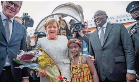  ?? FOTO. MICHAEL KAPPELER/DPA ?? Zweite Station Ghana: Kanzlerin Angela Merkel, hier mit Entwicklun­gsminister Gerd Müller (CSU) und Ghanas Vizepräsid­ent Mahamudu Bawumia (r), wird von einem Kind zum Empfang mit Blumen bedacht.