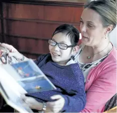  ?? CHAD HIPOLITO/THE CANADIAN PRESS ?? Isabelle Smit, 10, is photograph­ed with her mother Kristen Lundgren as they share a moment while looking through a family photo album in Esquimalt, B.C., on Tuesday. Through an online video the mother and daughter are hoping to find Isabelle’s birth parents or relatives.