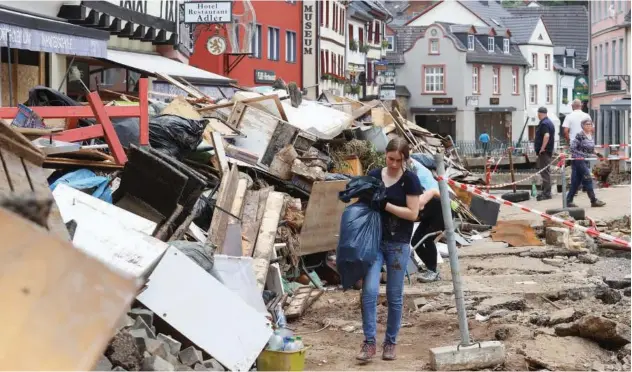  ?? Reuters ?? ↑ A woman carries a bag in an area, affected by floods, caused by heavy rainfall in Bad Muensterei­fel, Germany, on Monday.