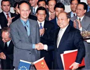  ??  ?? Shi Guangsheng (right front), Chinese minister of foreign trade, and Pascal Lamy (left front), EU trade commission­er, shake hands to mark the moment they sign the accord on China’s accession to the WTO on May 19, 2000.