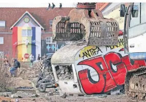  ?? FOTOS (2): ROLF VENNENBACH/DPA ?? Ein Bagger greift nach einem Wohnwagen.