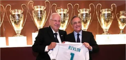  ??  ?? PRESIDENT REUVEN RIVLIN receives his Real Madrid shirt from the soccer club’s president Florentino Perez yesterday.