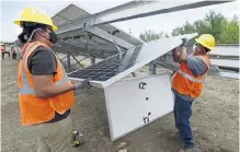  ?? Cliff Grassmick, Daily Camera ?? Tahahawat Sablan, left, and Mel Cody put in a solar panel Friday while Boulder Housing Partners and members of GRID installed solar panels at 4800 28th St. in Boulder. The 3.8- acre solar garden would be the first in the city to serve only low- income households.