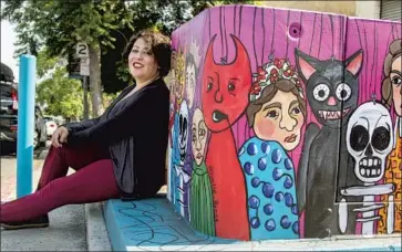  ?? Brittany Cruz-Fejeran San Diego Union-Tribune ?? ARTIST YVETTE ROMAN poses next to her piece “Títeres” — which means “puppets” in Spanish — one of a dozen utility box paintings recently completed in the Sherman Heights neighborho­od of San Diego.