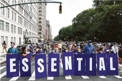  ?? Michael M. Santiago / Getty Images ?? Members of the 32BJ union hold up signs during a rally Monday in New York City that was part of the “Strike for Black Lives” campaign. Also there, the Service Employees Internatio­nal Union held a socially distanced rally and press event demanding passage of the Health and Economic Recovery Omnibus Emergency Solutions Act, or Heroes Act.