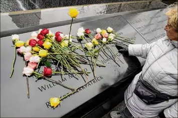  ?? Photos by John Minchillo / Associated Press ?? Mourners on Sunday place flowers over the names of the victims of the 1993 World Trade Center bombing during a ceremony at the 9/11 Memorial in New York City.