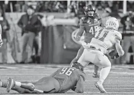  ?? Wade H. Clay / Midland Reporter-Telegram ?? Texas quarterbac­k Sam Ehlinger (11) was hard for Broderick Washington Jr. and the Texas Tech defense to contain Saturday night at Lubbock. Although Ehlinger was sacked five times, he passed for 312 yards and four touchdowns in the Longhorns’ 41-24 victory.