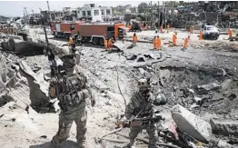  ?? GETTY-AFP ?? Afghan forces keep watch as municipal workers clean up a blast site Tuesday in Kabul.